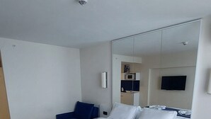 A hotel room with a large bed, a desk, a chair, a flat-screen TV, and a microwave. - Beautiful Studio Apartment in Batumi (Batumi)