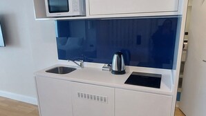 A compact kitchenette with a microwave, kettle, and sink. - Beautiful Studio Apartment in Batumi (Batumi)