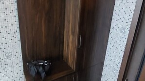 A corner room with a wooden wardrobe, a small bench, and a tiled wall. - Orbi Sea Towers Batumi (Batumi)