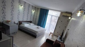 A modern hotel room with a bed, a sofa, a desk, and a bathroom. - Orbi Sea Towers Batumi (Batumi)