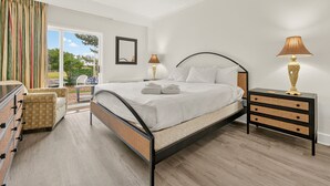 Ein Schlafzimmer mit einem Bett, zwei Nachttischen, einer Kommode und Blick ins Freie.
