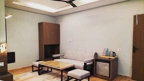 A compact living space with a sofa, a small table, a cabinet, and a ceiling fan. - The Foresta (Dhari)