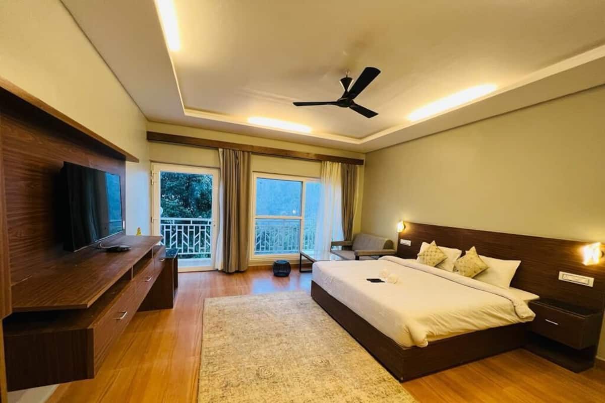 A bedroom with a bed, bedside tables, a TV, a ceiling fan, and a view of the outdoors.