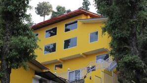A multi-story yellow building with a red roof, white railings, and a staircase leading to the upper floors. - The Foresta (Dhari)