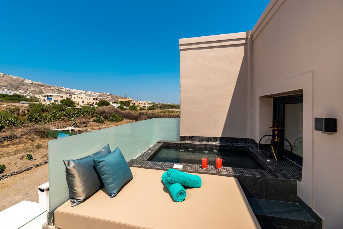 Ein Balkon mit Whirlpool, Blick auf eine Hügelterrasse sowie Handtuch und Kissen auf der Sitzecke.