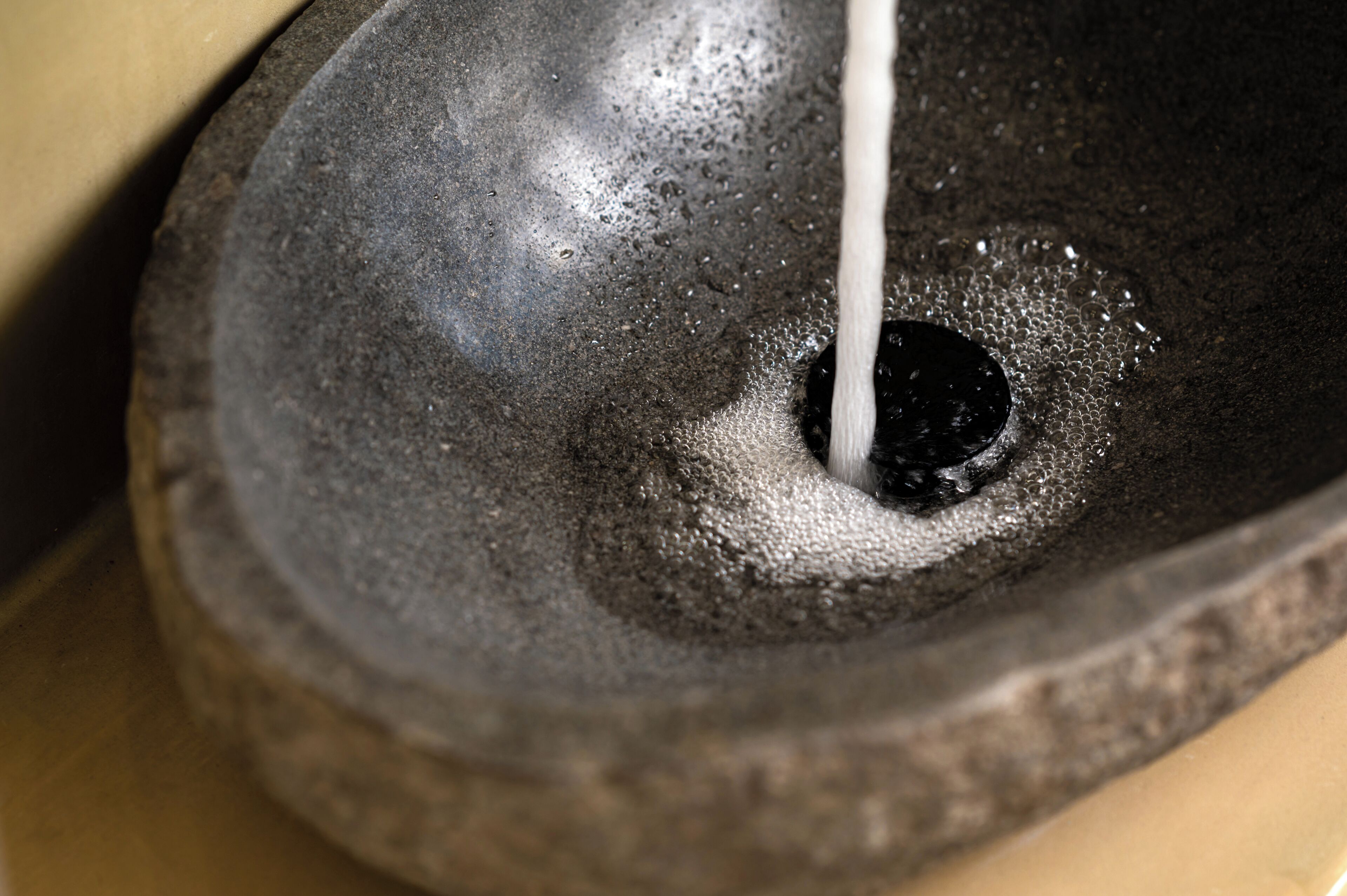 A close-up of a stone mortar with a liquid being poured into it.
