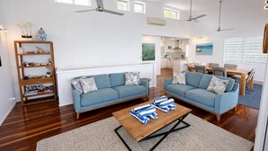Una sala de estar moderna con dos sofás, una mesa de centro, una estantería y un comedor con una mesa y sillas.