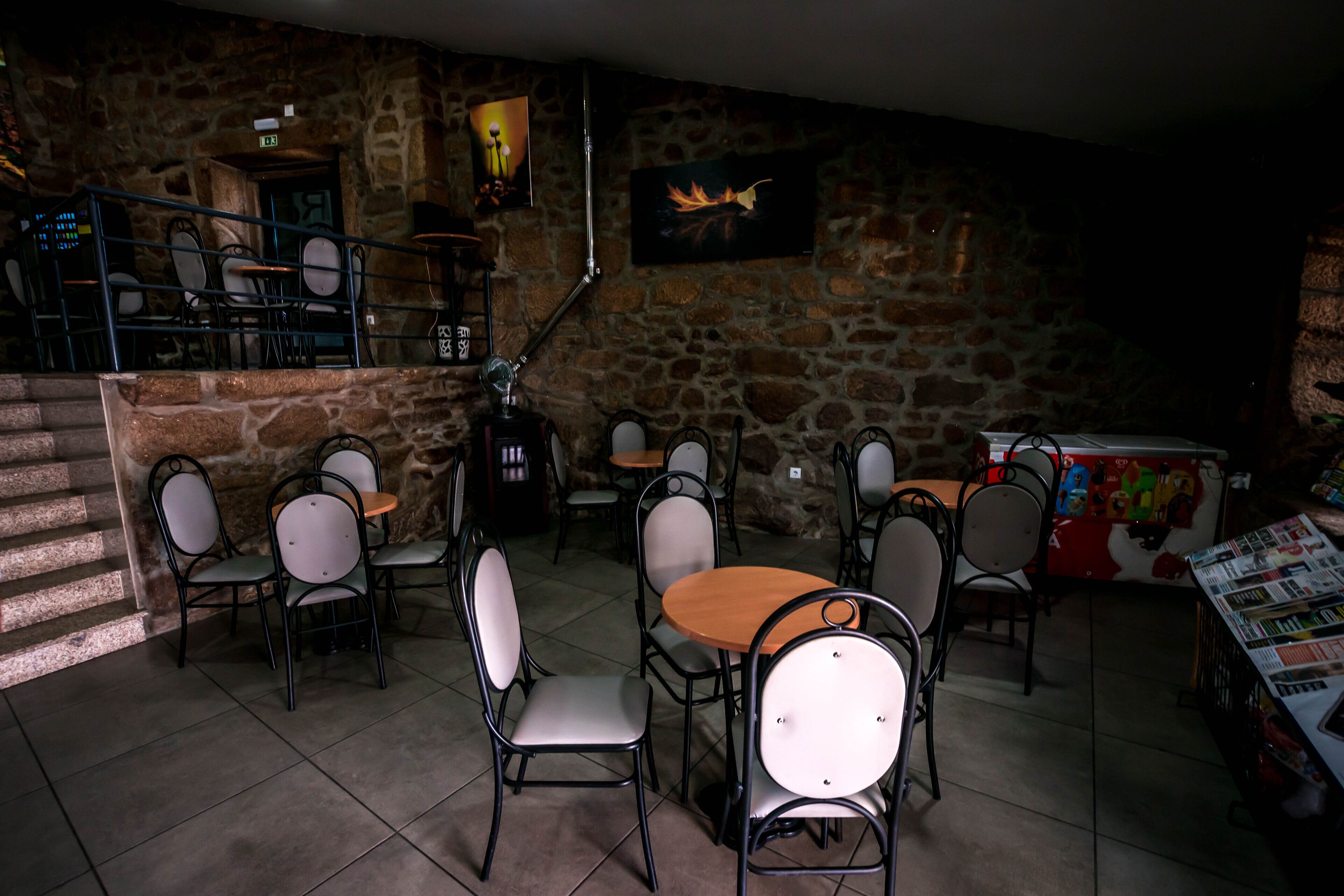A restaurant with stone walls, multiple tables and chairs, and a staircase leading to an upper level.