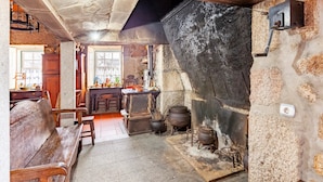Una cocina rústica con paredes de piedra, un banco de madera y diferentes utensilios de cocina.