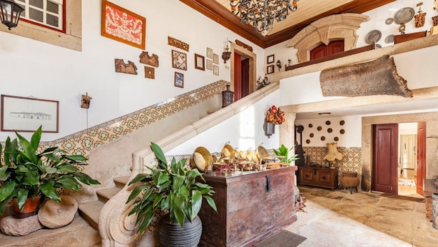 Un vestíbulo amplio con una escalera de piedra, un mostrador central de madera y diversas decoraciones en las paredes.
