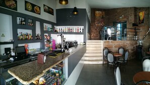 A bar area with a counter, shelves of bottles, and a seating area with tables and chairs.