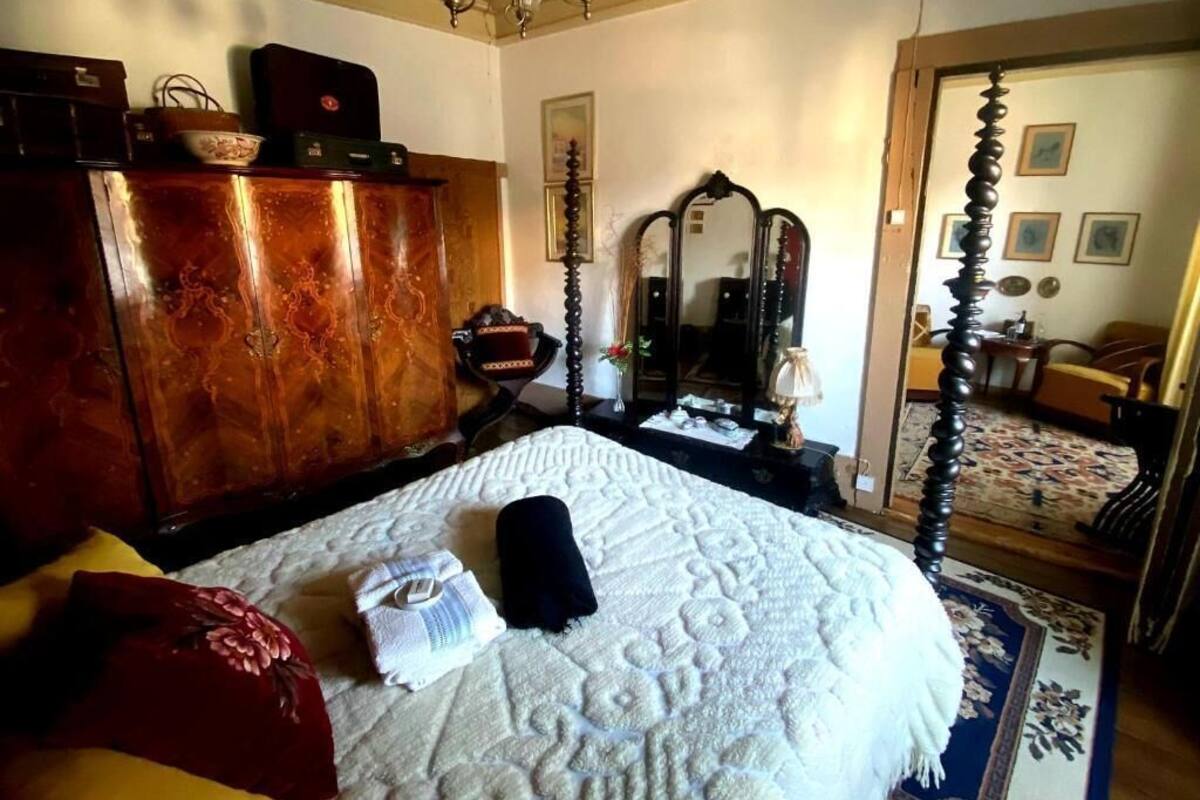 Un dormitorio con una cama grande, un armario de madera, un espejo y una araña.