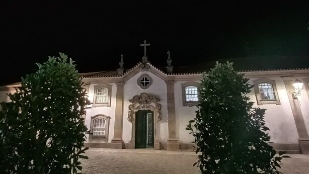 A church with a green door, arched windows, and a cross on the roof.