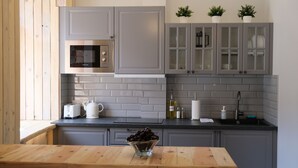 Une cuisine moderne avec des meubles gris, un four à micro-ondes encastré, une bouilloire et un bol de cerises posé sur le plan de travail.