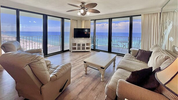 A spacious living room with a large flat-screen TV, comfortable seating, and a balcony with ocean views. - 2BR/2BA End Unit, Pool , Prvt Covered Parking, Seasonal Beach Serv. (Panama City Beach)