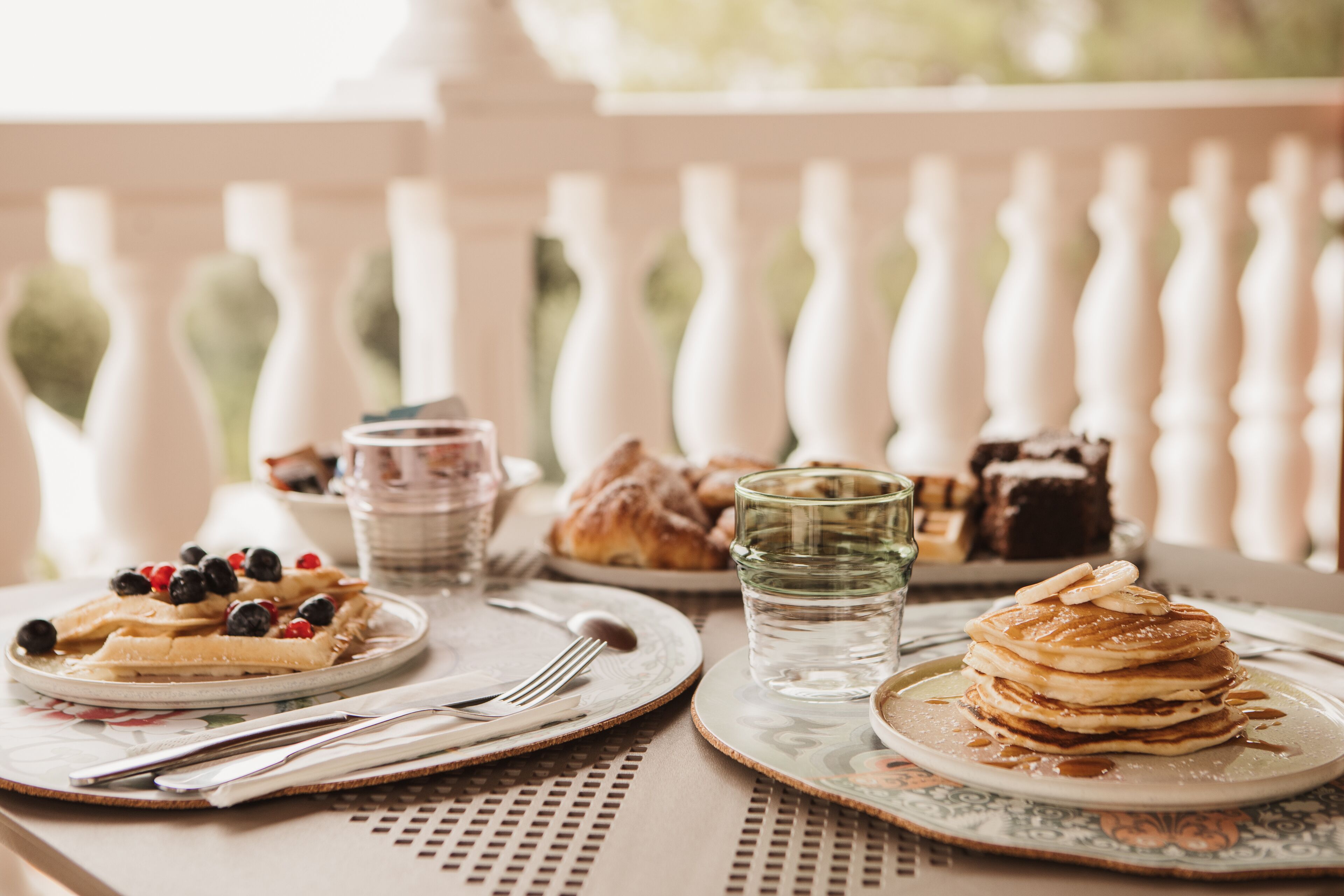 A breakfast table with waffles, pastries, and a glass of water.