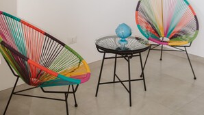 A room with white walls, a round table, and two colorful chairs. There are framed pictures on the wall. - Monte Simeone B&B (Polignano a Mare)