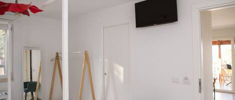 A room with a bed, a chair, a TV, and a door.