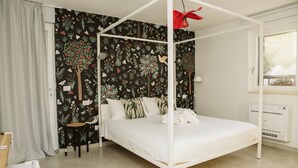 A bedroom with a canopy bed, a black floral wallpaper, a white ceiling fan, and a window with a view. - Monte Simeone B&B (Polignano a Mare)