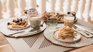 A breakfast table with waffles, pancakes, and pastries, along with cups and a glass of water. - Monte Simeone B&B (Polignano a Mare)