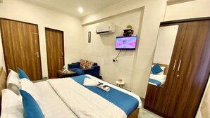 Een hotelkamer met een groot bed, een aan de muur bevestigde televisie, een klein tafeltje en een kast.