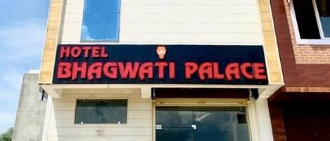 A hotel named BHAGWATI PALACE with a modern facade, large entrance doors, and a prominent sign.