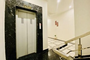 An elevator with a sign reading "1st FLOOR" and a staircase with a metal railing. - Hotel bhagwati palace (Jaipur)