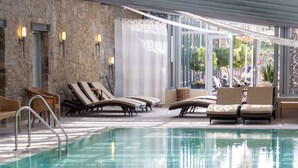 Ein Hallenbad mit Liegestühlen und einer Steinwand.