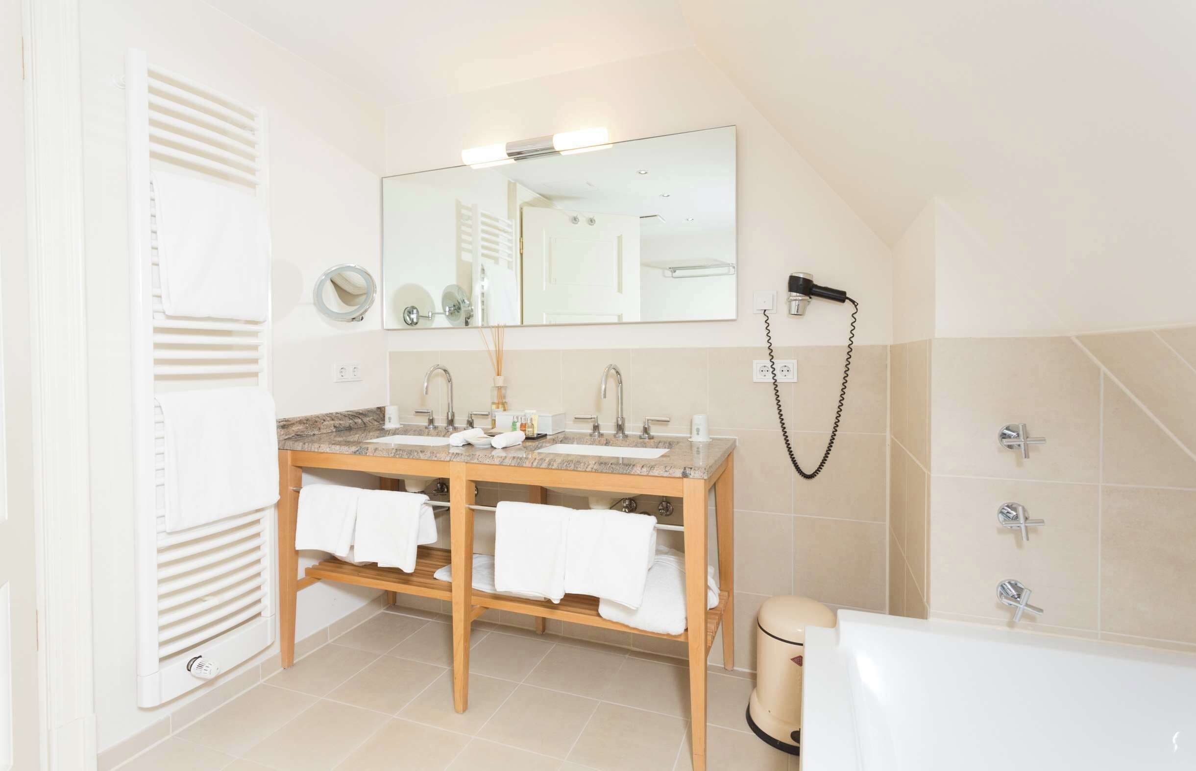 Ein Badezimmer mit einem Holztisch, zwei Waschbecken, einem großen Spiegel, einem Handtuchhalter, einer Dusche und einer Badewanne.