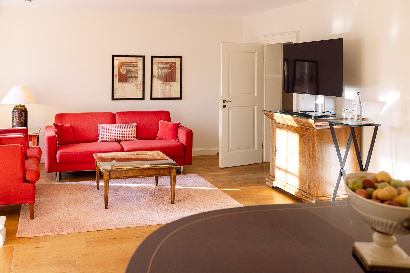 A living room with a red sofa, a coffee table, a TV, and a cabinet with a glass top.