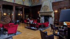 Eine großzügige Lobby mit Kamin, roten Polstersesseln und Holzboden.