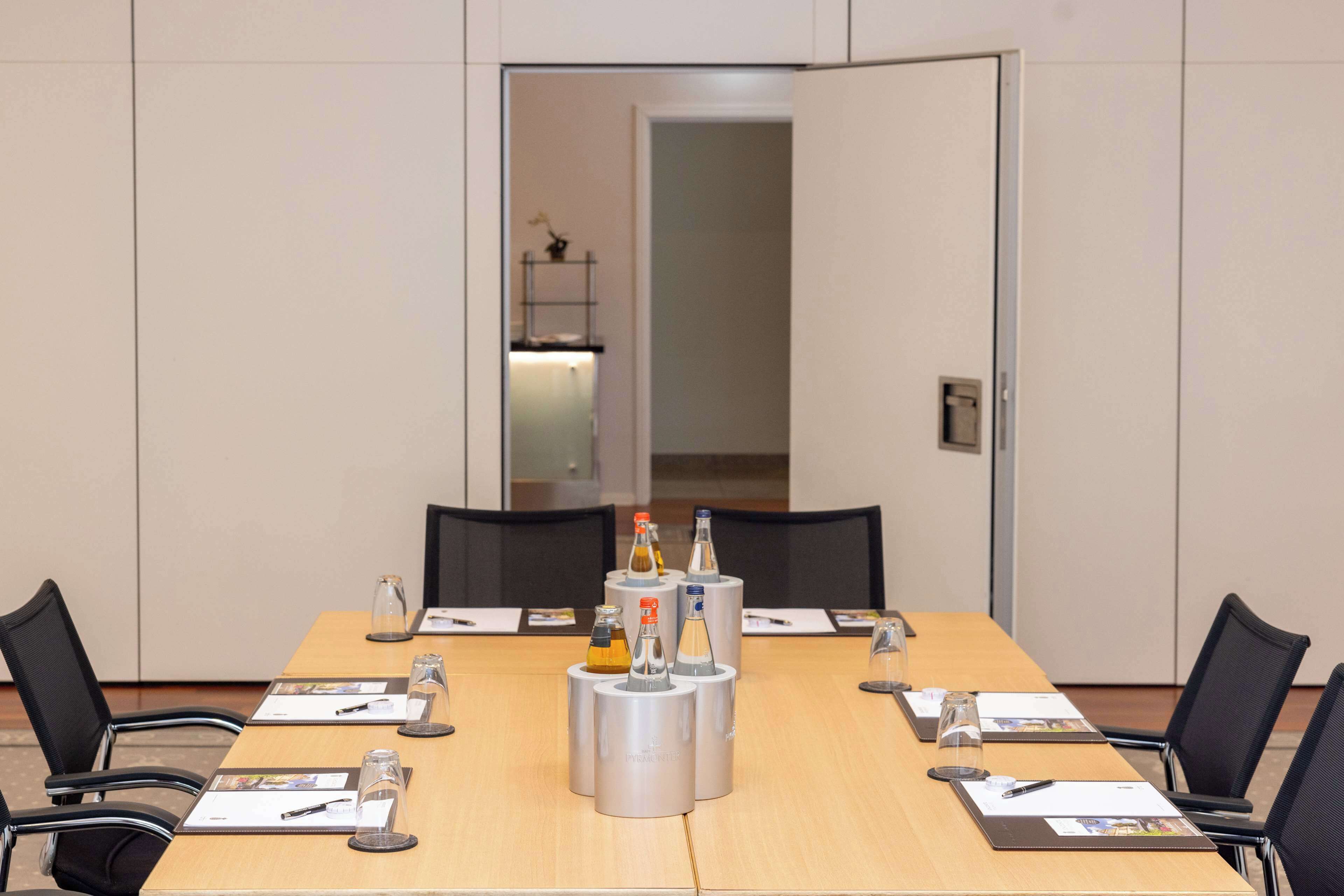 Ein Konferenzraum mit einem langen Tisch, schwarzen Stühlen und einer Glastrennwand.