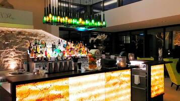 A bar area with a variety of bottles and glasses, a decorative light fixture, and a modern interior design.
