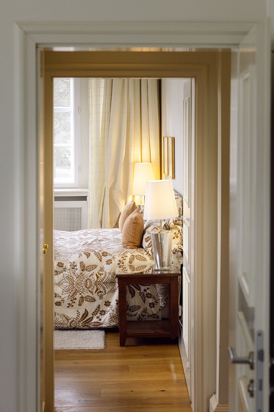 Une chambre à coucher avec un lit, deux lampes de chevet, une table de chevet et une fenêtre avec des rideaux.