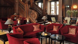 Eine prachtvolle Lobby mit roten Samsofas, einer Treppe und aufwendigen Wandverzierungen.
