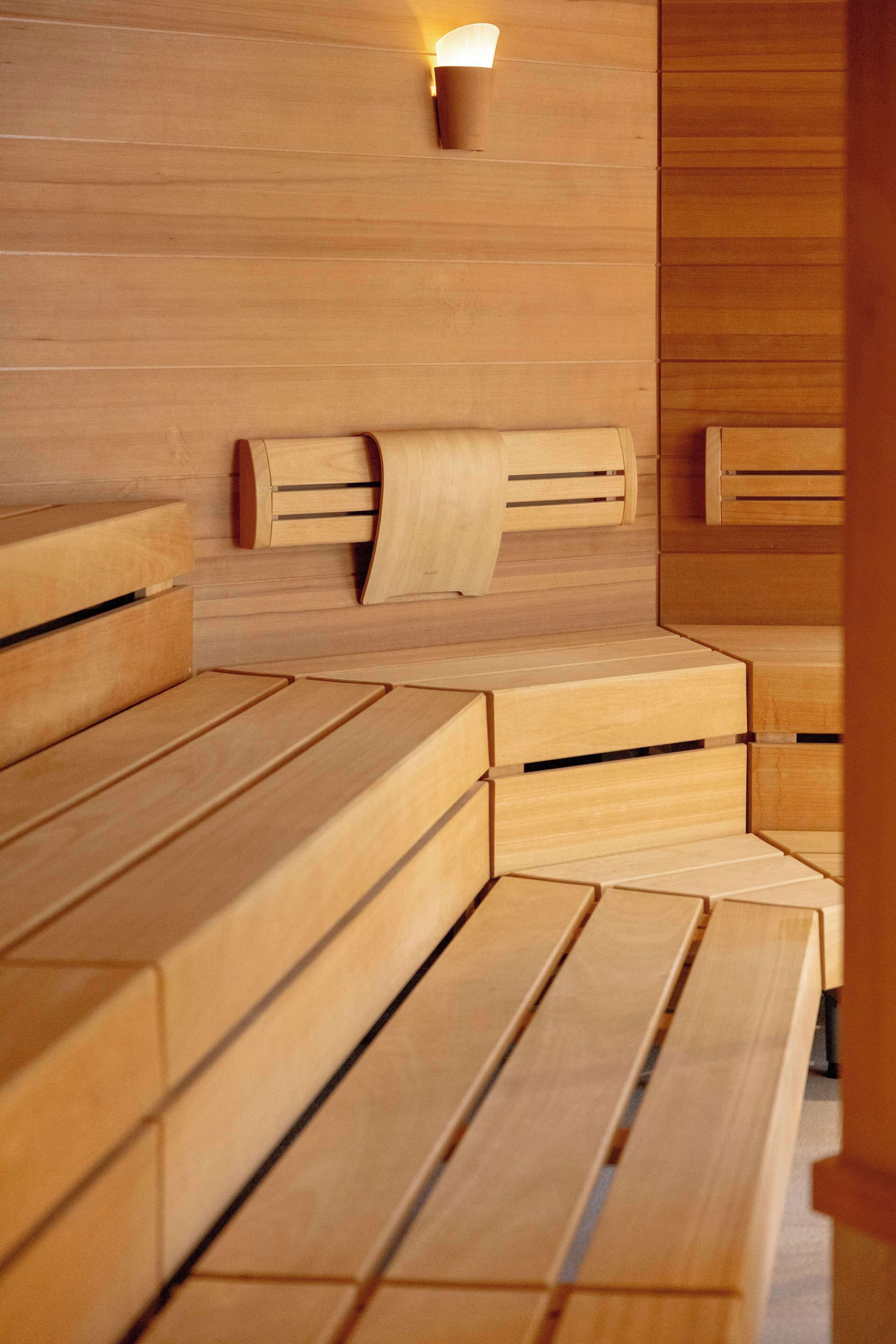 A wooden sauna with benches and a wall-mounted light fixture.