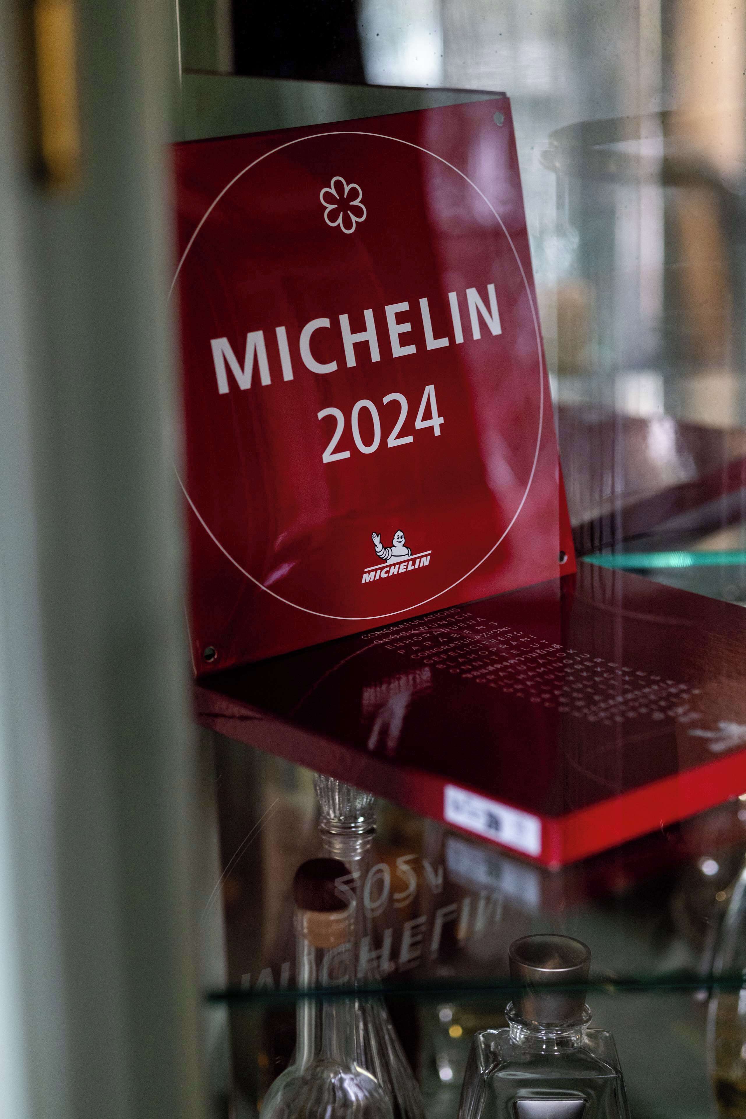 A red sign with the text "MICHELIN 2024" and a logo, placed on a shelf with various items.
