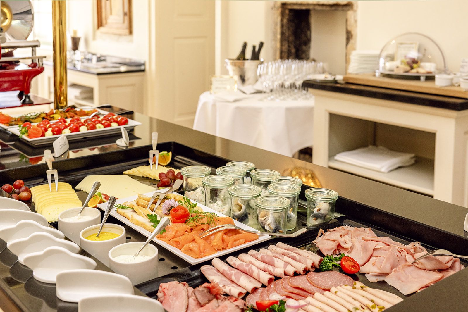 A buffet with various food items including meats, cheeses, and fruits.