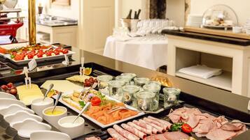 A buffet with various food items including meats, cheeses, and fruits.