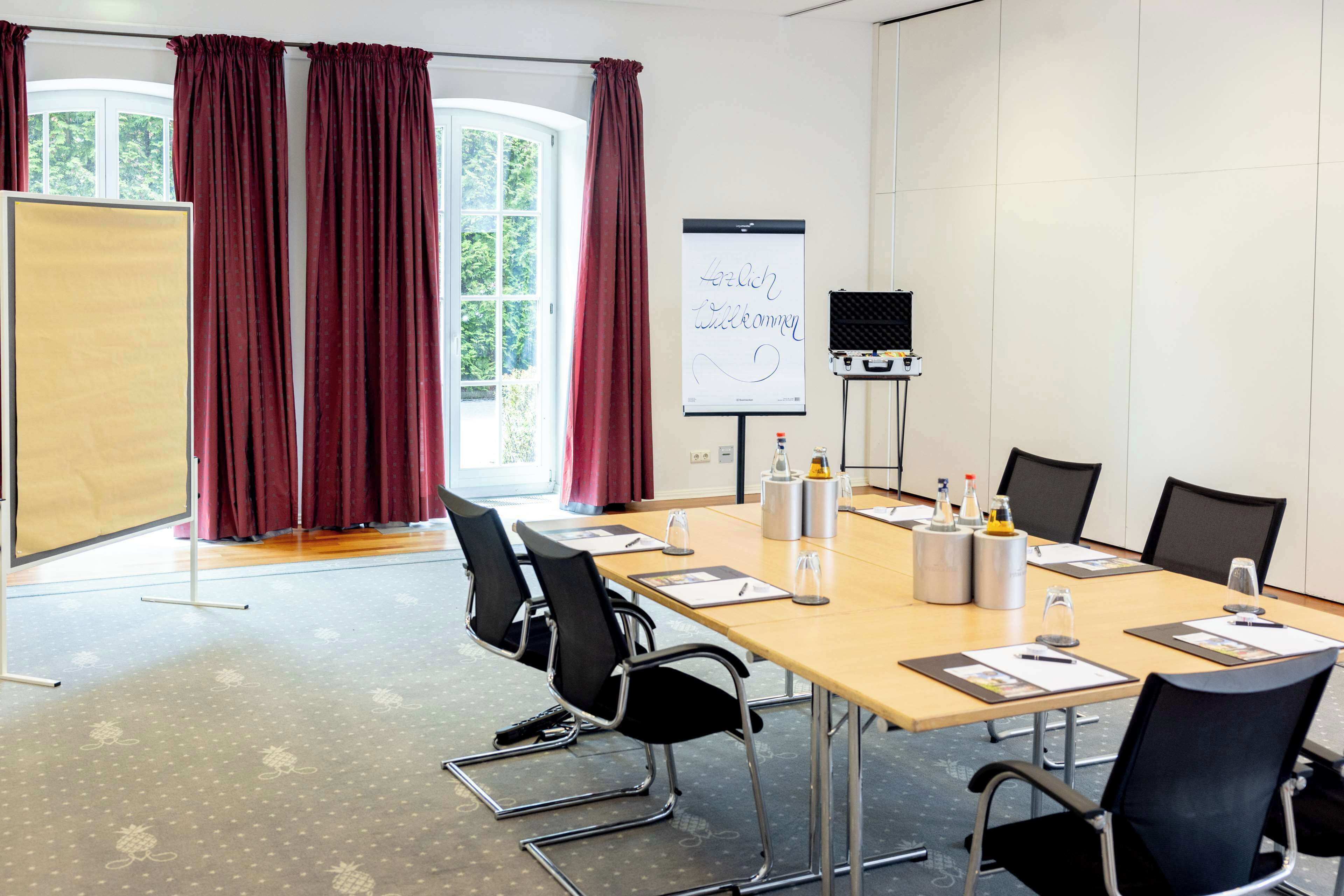 A conference room with a long table, black chairs, a whiteboard, and a projector screen.