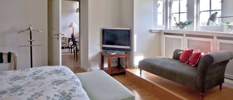 A bedroom with a bed, a chair, a TV, and a window with a view.