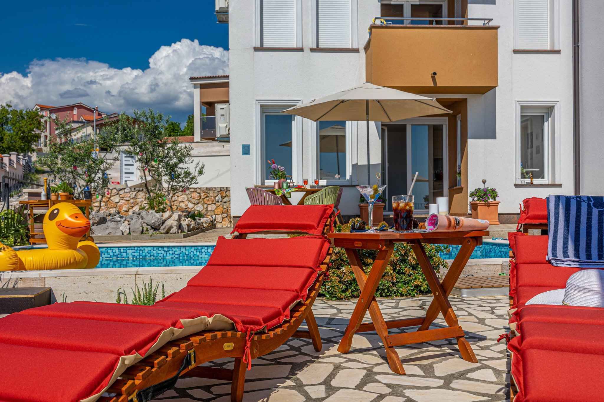 A poolside area with lounge chairs, a table, and a yellow inflatable duck.