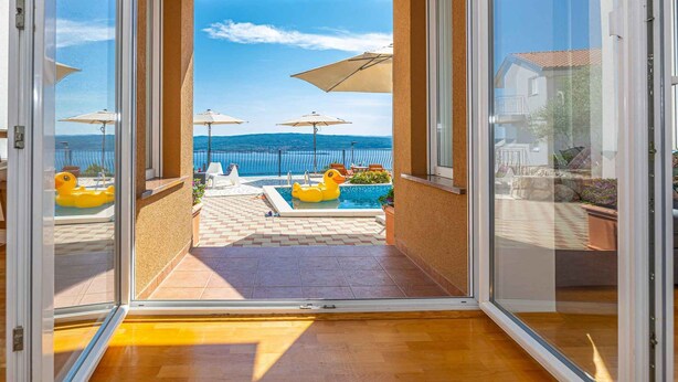 Een balkon met uitzicht op een zwembad en de zee.