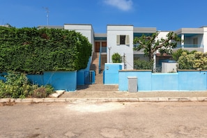 A residential building with a blue exterior, a staircase leading to a door, and a clear blue sky.