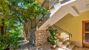 A stone staircase leading to a second floor, surrounded by greenery and a potted plant. - Holiday apartment with balcony and sea view (Selce)
