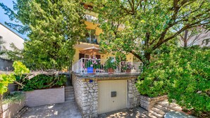 Un edificio a due piani con un balcone, pareti in pietra e un ingresso recintato.