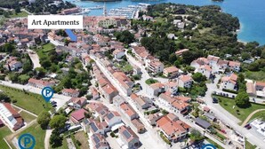 Vista aérea de uma área residencial com apartamentos de design, vagas de estacionamento demarcadas e o mar ao fundo.