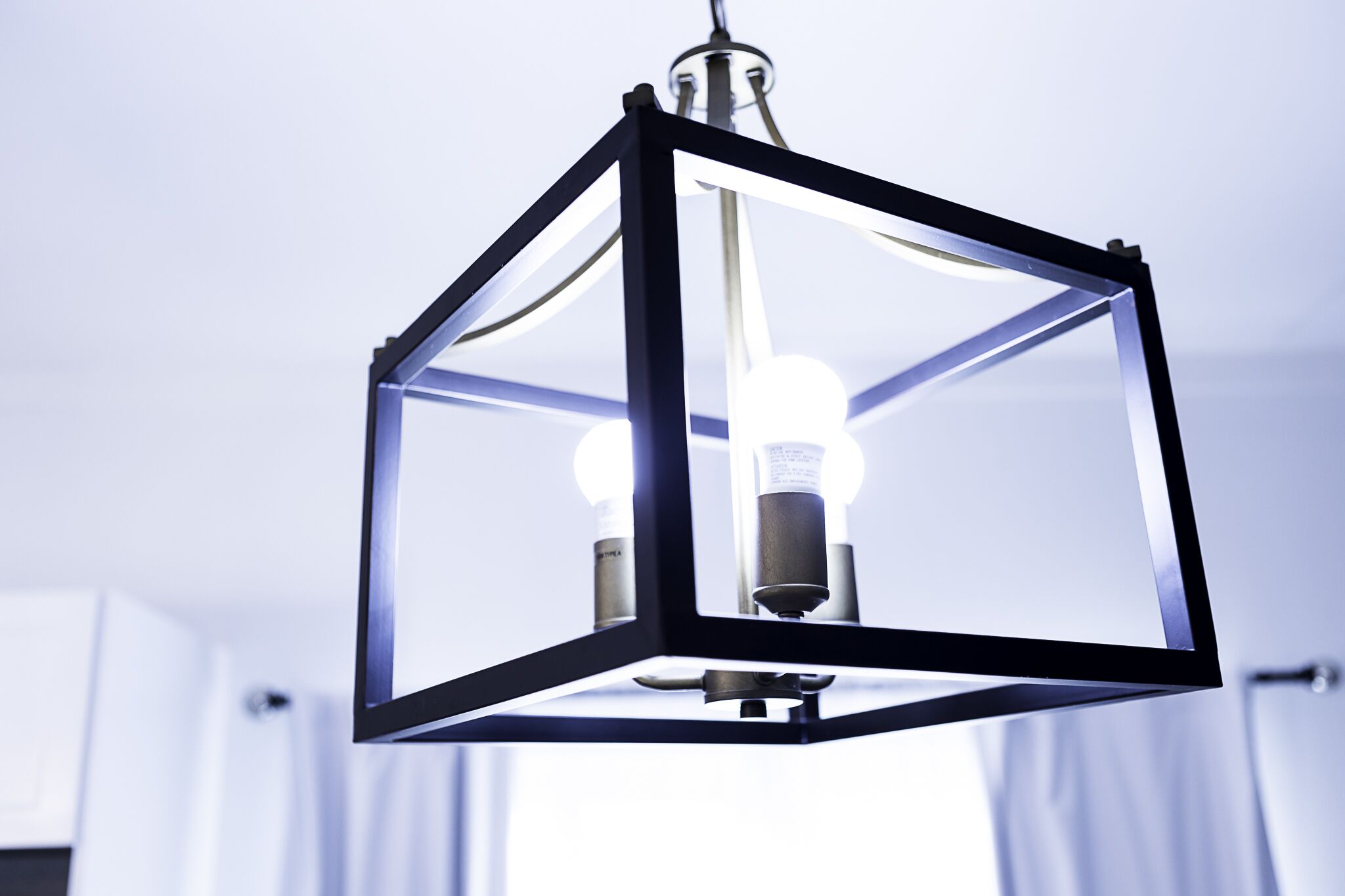 Un lustre moderne doté d’une structure géométrique et d’ampoules apparentes.