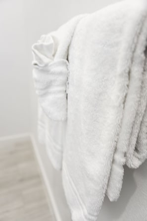 Une serviette blanche est accrochée à un mur dans une salle de bain.