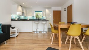 A modern kitchen with white cabinets, a black countertop, and a window with a view of greenery. - Hen Gapel (Caernarfon)